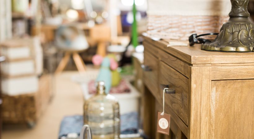 A second hand furniture store, with an antique set of drawers and a lamp.