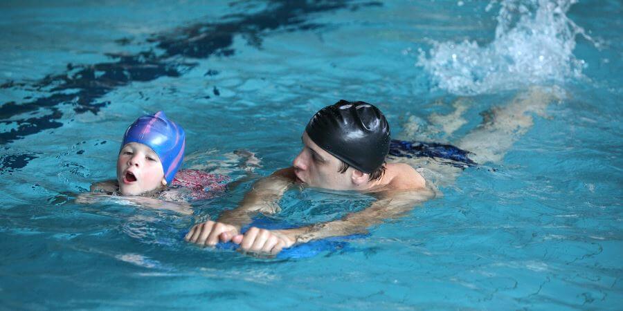 An adult teaching a child to swim.