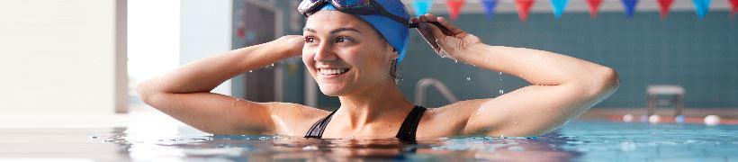A smiling swimmer adjusting her goggles.