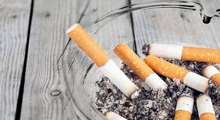 Used cigarettes in a full ashtray.