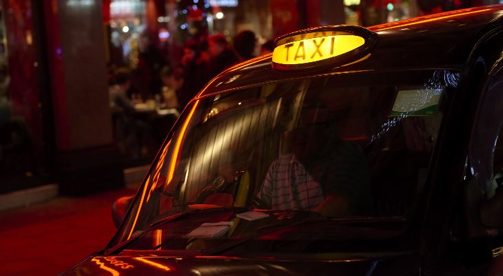 A taxi waiting outside a venue at night.