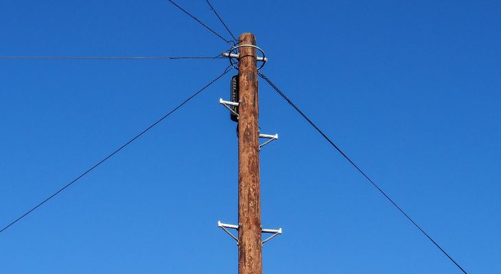 A standard UK wooden telegraph pole against a blue sky.