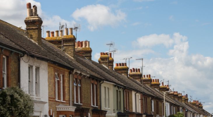 A row of terrace houses under a blue, cloudy sky.