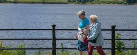 Two visitors strolling past Hollingworth Lake.