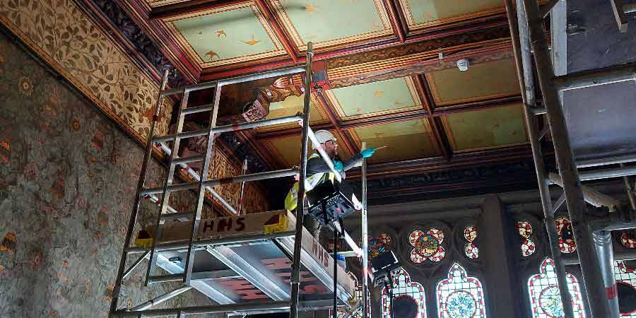 A worker examining ceiling tiles in Rochdale Town Hall. 