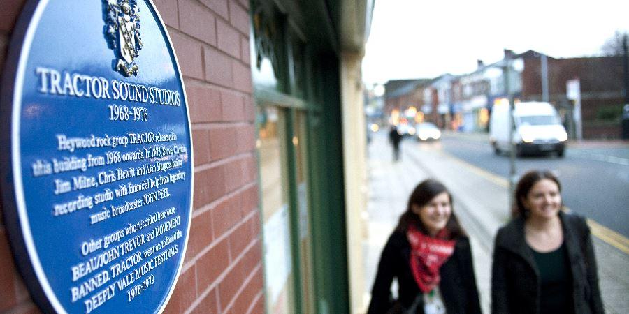 2 women walking past the blue Tractor Sounds Studios plaque.