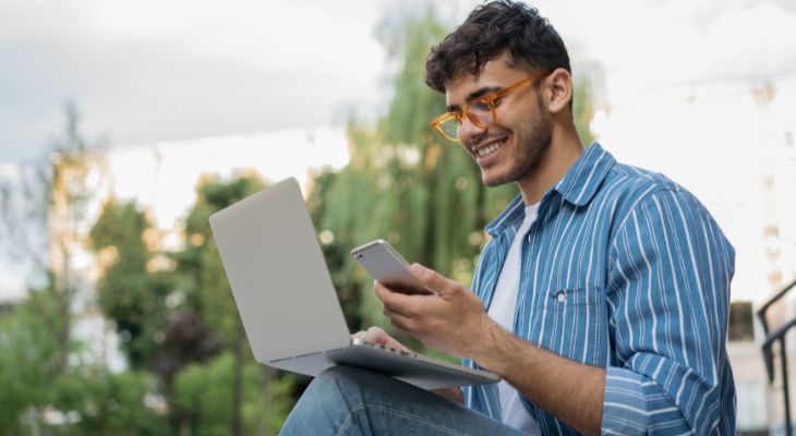 A man using his computer and mobile phone.