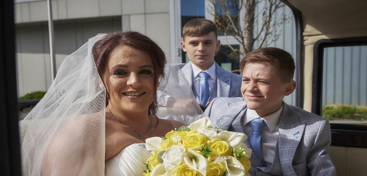 Bride and page boys sat in wedding car.