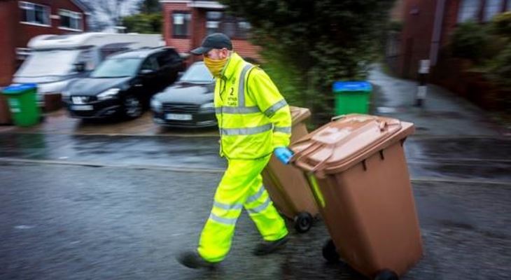 A bin team operator taking recycling bins to the waiting lorry.
