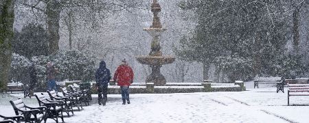 A couple walking in the snow at Queens Park,.